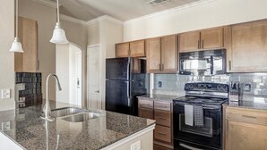 A modern kitchen with granite countertops, stainless steel appliances, and wooden cabinets. - Landing | Spectacular 1BD, Clubhouse, Pool (Grand Prairie)