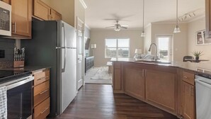 Eine moderne Küche mit Holzausstattung, einem Edelstahlkühlschrank und einer schwarzen Arbeitsplatte.