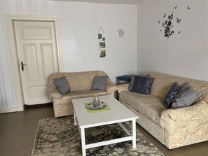 Ein Wohnzimmer mit einem beigefarbenen Sofa, einem weißen Couchtisch und einem gemusterten Teppich.