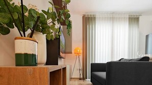 Un salon moderne avec une table basse en bois, un canapé noir et un lampadaire.