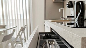 Une cuisine moderne dotée d'un système de rangement intégré dans les tiroirs, d'une machine à café et d'une fenêtre avec des stores.