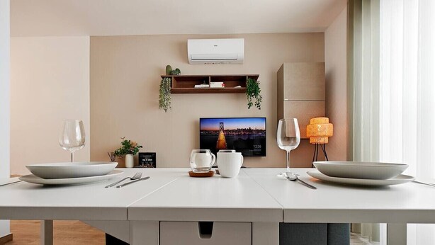 Un espace repas moderne avec une longue table, deux bols, un pichet blanc et un verre.