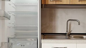 Une cuisine moderne avec des meubles blancs, un évier en acier inoxydable et des placards en bois situés en hauteur.