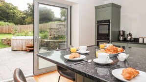 A modern kitchen with a breakfast setup including croissants, orange juice, and coffee. - Knowle House (Okehampton)