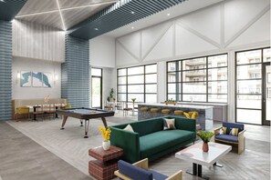 Een ruime lobby met een pooltafel, een groene bank en een bar.