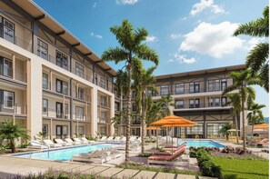A hotel with a pool area, palm trees, and outdoor seating. - Landing | Beautiful Studio, Game Room, Gym (Jacksonville)