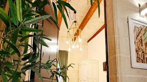 A room with a bed, a chandelier, and a large plant. - Casa Maltija Sliema 4 Bedroom (Sliema)