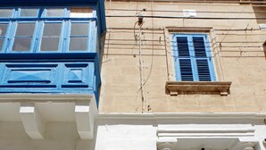 A building facade with a white and blue color scheme, featuring a prominent blue door with a decorative arch and columns. - Casa Maltija Sliema 4 Bedroom (Sliema)