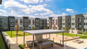Un moderno complejo de apartamentos con varios balcones, un patio exterior cubierto y un césped bien cuidado.