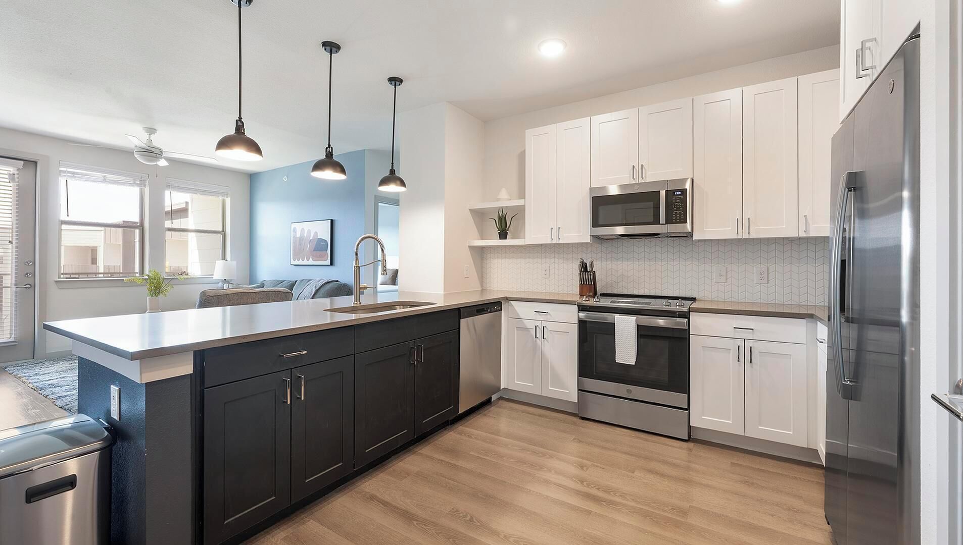 A modern kitchen with a central island, stainless steel appliances, and pendant lighting.