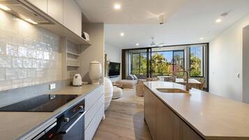 A modern kitchen with a built-in oven, a coffee machine, and a large island with a sink.