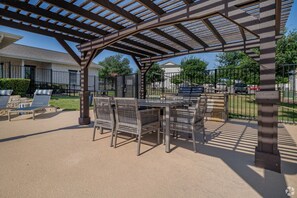 An outdoor patio with a pergola, a table with chairs, and a pool area. - Landing | Amazing 2BD, Gym, Clubhouse (San Antonio)