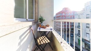 A balcony with a table set for breakfast, a chair, and a potted plant. - Nine Horizons Central (Lisbon)