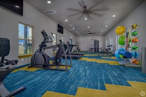 Ein Fitnessstudio mit Laufbändern, Crosstrainern und Kurzhanteln.