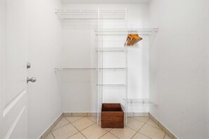 Un coin de pièce avec une porte blanche, une étagère en métal et un panier en osier.