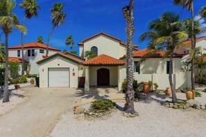 A residential building with a red-tiled roof, a garage, and a driveway leading to the entrance. - Private pool • BBQ • Ocean views (Noord)