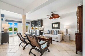 A spacious living area with a dining table, two sofas, and a ceiling fan. - Private pool • BBQ • Ocean views (Noord)