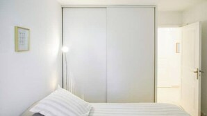 Un dormitorio con cama, armario y puerta que da a otra habitación.