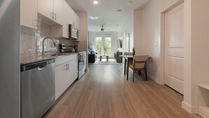 Een moderne keuken met roestvrijstalen apparatuur, een eethoek met een tafel en stoelen, en een gang naar een deur.