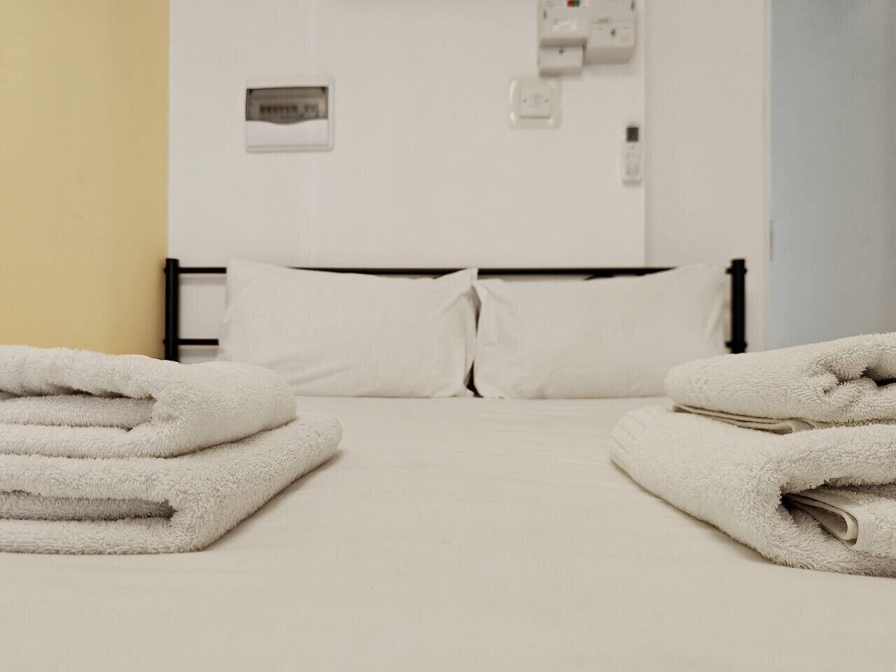 Un lit bien fait, avec des draps blancs et deux serviettes pliées de chaque côté.