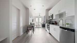 Een moderne keuken met witte kasten, een ingebouwde magnetron en een vaatwasser.