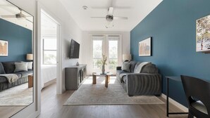Een moderne woonkamer met een bank, een salontafel en een aan de muur bevestigde televisie.