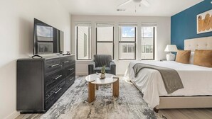 Een moderne slaapkamer met een groot bed, een dressoir, een stoel en een televisie.