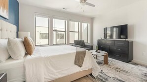 A bedroom with a bed, a TV, a dresser, and a chair. - Landing | Stunning Studio, Gym, Pool (Austin)