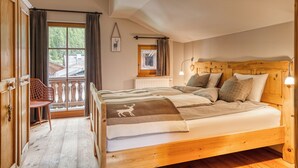 Ein Bett mit Holzkopf, zwei Nachttische und ein Fenster mit Vorhängen.