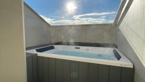Un bain à remous doté d’une ouverture dans le toit, offrant une vue sur le ciel, et d’une sortie de vapeur.