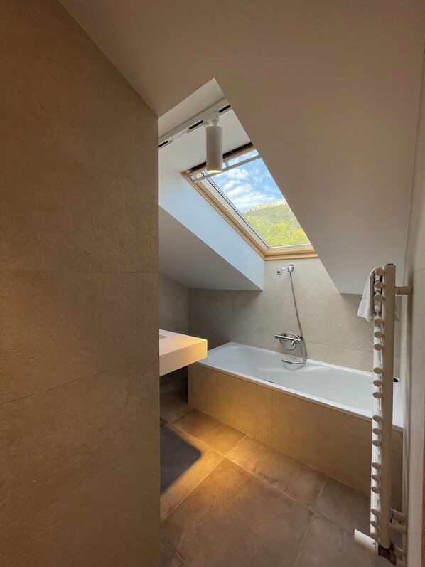 Un baño moderno con tragaluz, bañera y tocador.
