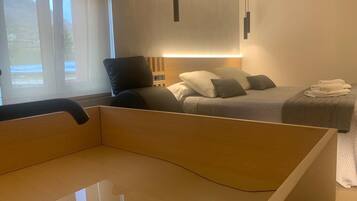 Een moderne slaapkamer met een houten hoofdbord, een bed met grijze beddengoed en een nachtkastje.