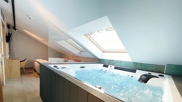 Une salle de bain moderne avec une baignoire sur pieds, un puits de lumière et un petit coin salon.