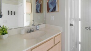 A bathroom with a white sink, a mirror, a potted plant, and two abstract paintings on the wall. - Landing | Stylish 2BD, Gym, Clubhouse (Pasadena)