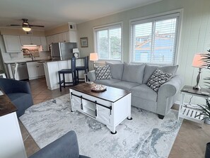 Een moderne keuken met witte kastjes, een koelkast en een eethoek met twee stoelen.