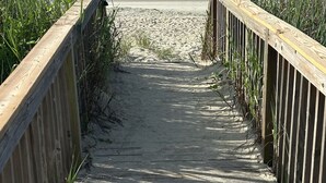 A wooden boardwalk leading to a beach with two people walking. - Anchor & Dreams - Peaceful Updated 2BR Oceanfront Condo (Ocean Isle Beach)