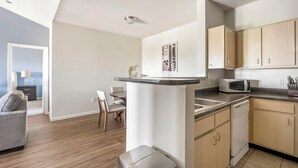 A compact kitchen with wooden cabinets, a microwave, and a dining area with a table and chairs. - Landing | Incredible 2BD, Pool, Gym (Pasadena)