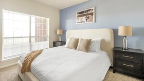 A bedroom with a large bed, two bedside tables, a nightstand, and a window with blinds. - Landing | Incredible 2BD, Pool, Gym (Pasadena)