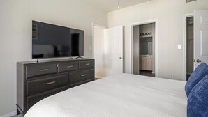 Une chambre à coucher avec un grand lit, une commode avec des tiroirs, un miroir et un placard dont la porte est ouverte.