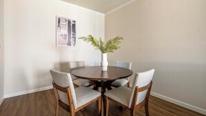 Un coin repas avec une table ronde, quatre chaises et un vase orné de feuillage vert.