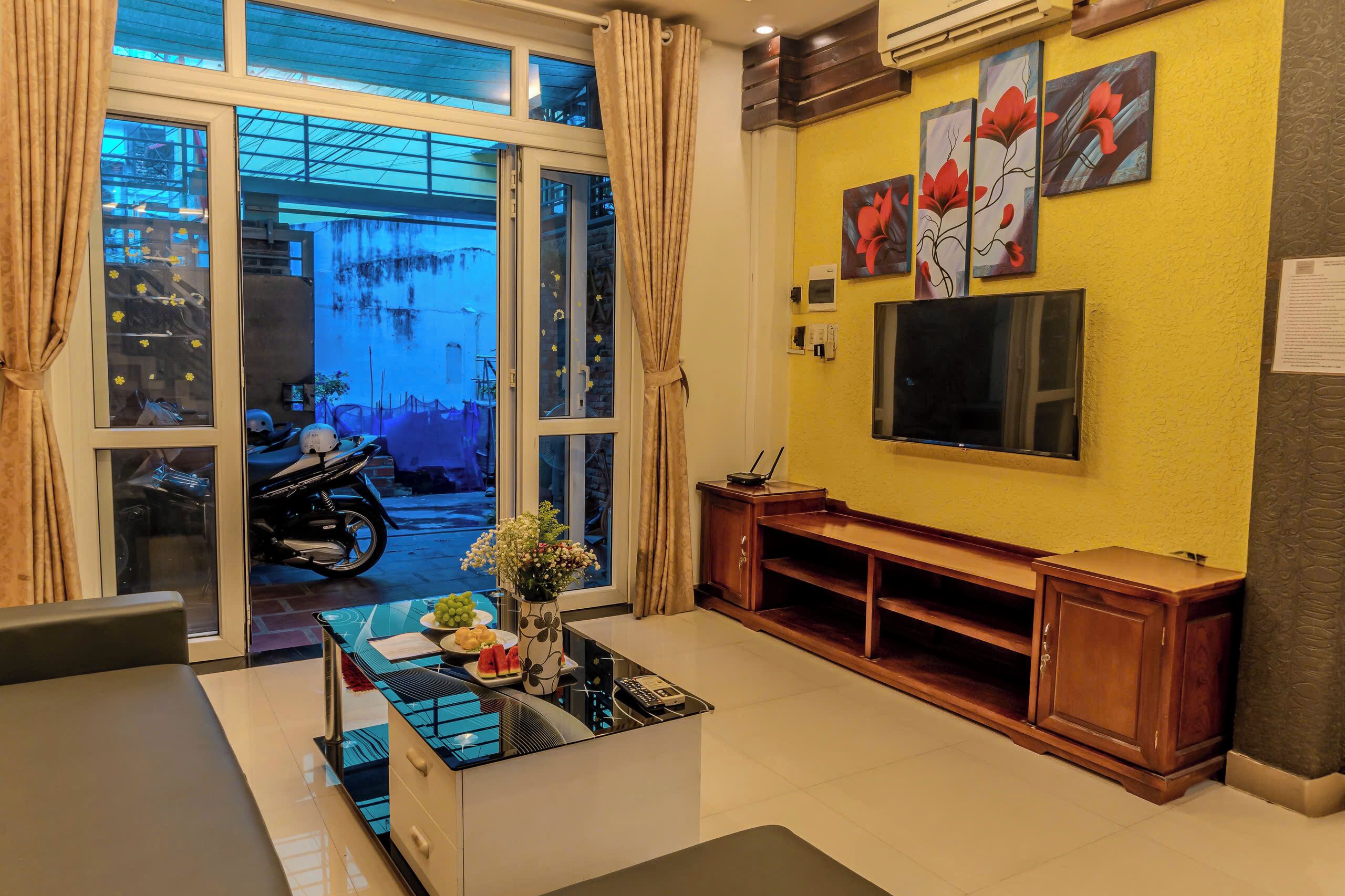 Een woonkamer met een bank, salontafel, televisie en kunstwerk aan de wand.
