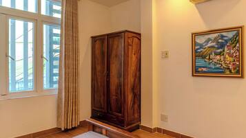 Ein Zimmer mit großem Holzschrank, einem Bild an der Wand und einem Fenster mit Vorhängen.