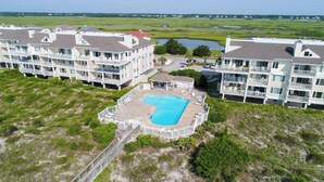 A large building with multiple balconies and a swimming pool. - Updated End Unit in Wrightsville Dunes with Loft and Oceanfront Views (Wrightsville Beach)