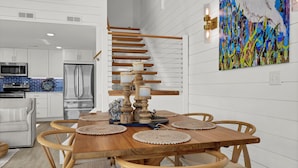 A modern kitchen with white cabinetry, stainless steel appliances, and a wooden staircase. - Updated End Unit in Wrightsville Dunes with Loft and Oceanfront Views (Wrightsville Beach)