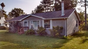 A single-story house with a gabled roof, a chimney, and a front porch. - Beautiful 2-bedroom house with AC in charming Germfask  Close to Pictured Rocks (Germfask)