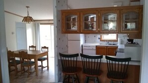 A kitchen with wooden cabinets, a dining table with chairs, and a refrigerator. - Beautiful 2-bedroom house with AC in charming Germfask  Close to Pictured Rocks (Germfask)