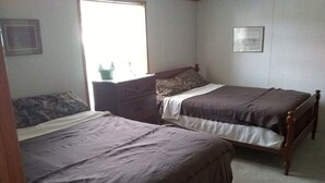 A bedroom with two single beds, a dresser, and a window providing natural light. - Beautiful 2-bedroom house with AC in charming Germfask  Close to Pictured Rocks (Germfask)