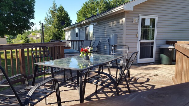 A patio with a glass table, metal chairs, and a flower vase. - Beautiful 2-bedroom house with AC in charming Germfask  Close to Pictured Rocks (Germfask)
