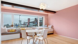 Ein modernes Interieur mit Essbereich, einer Couch mit Kissen und großen Fenstern mit Blick auf die Stadt.