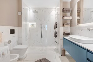 Une salle de bain moderne avec une douche à parois de verre, un lavabo blanc et un meuble-lavabo bleu.